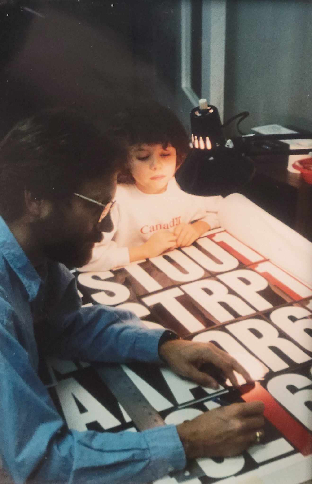 Young Claire looks on as her Dad, Rick, examines a film for screenprinting.