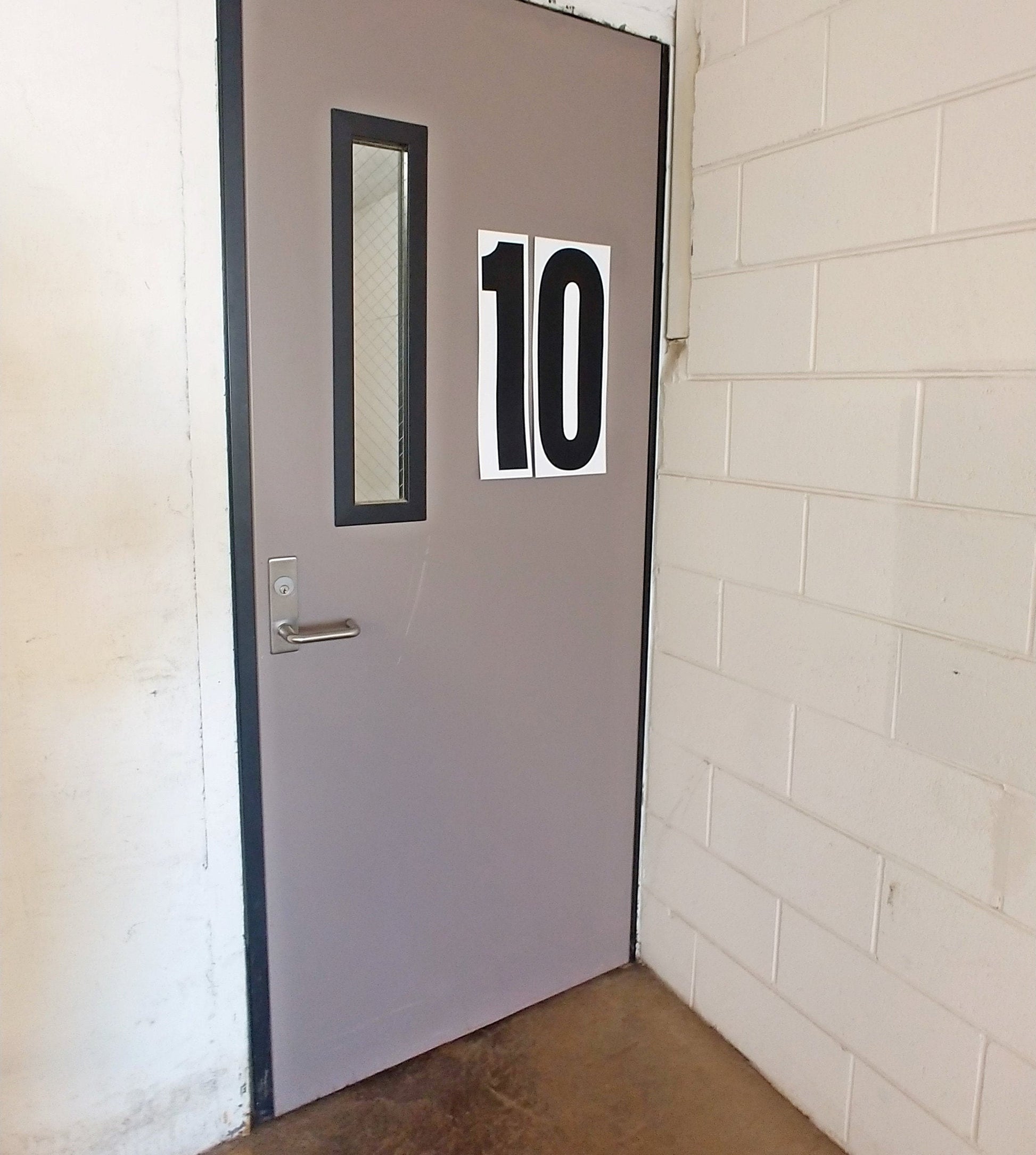 A grey door labeled "10" with 18inch tall numbers from the Stikons line of products by InkBird Print Studio. Black ink on white matte vinyl applied to the right of a window in the door.