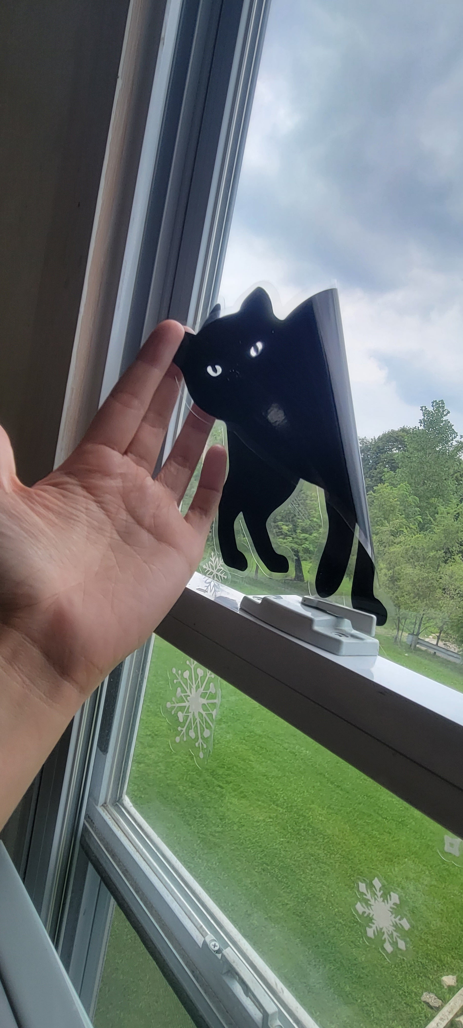 A hand pulls a static cling cat off of the window. Part of the window cling set for halloween "cats" by InkBird Print Studio. Thin plastic clings to the window via static, no adhesive, renter friendly.