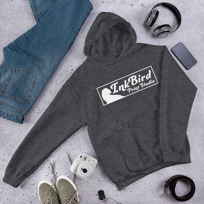 An InkBird Print Studio Unisex Hoodie from InkBird Print Studio LLC, offering a soft feel in gray, is displayed on a concrete surface. It is styled with blue jeans, headphones, a phone, a camera, and khaki sneakers for an overall fashionable appearance.